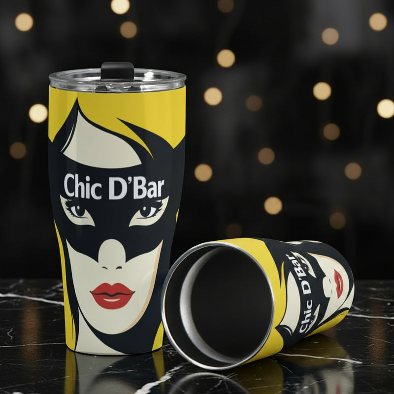 Metal tumbler with a graphic design of a face and 'Chic D'Bar' text on a gray surface.